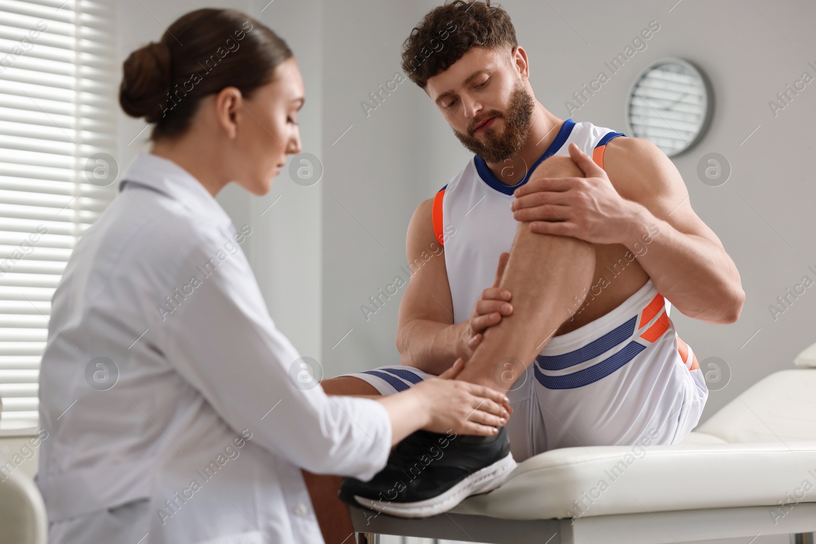 Photo of Sports injury. Doctor examining patient's leg in hospital