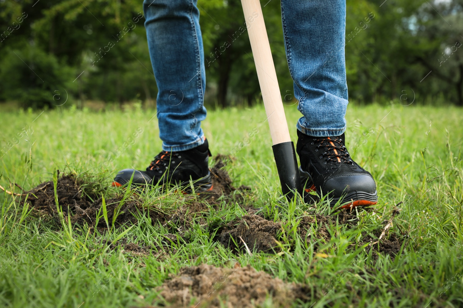 Photo of Worker digging soil with shovel outdoors, closeup