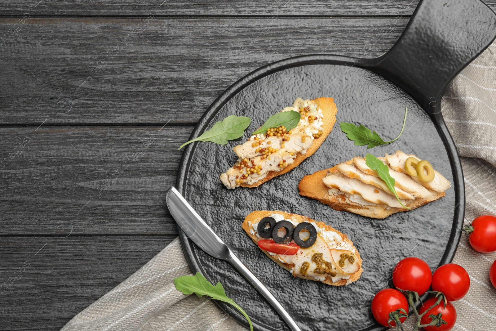 Photo of Slate plate of delicious chicken bruschettas on dark wooden table, flat lay. Space for text