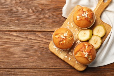 Photo of Tasty muffins served with banana on wooden table, top view. Space for text