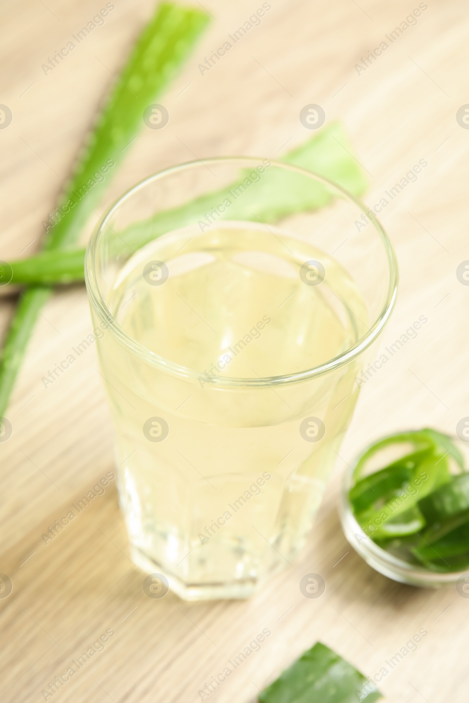 Photo of Fresh aloe drink in glass and leaves on wooden table