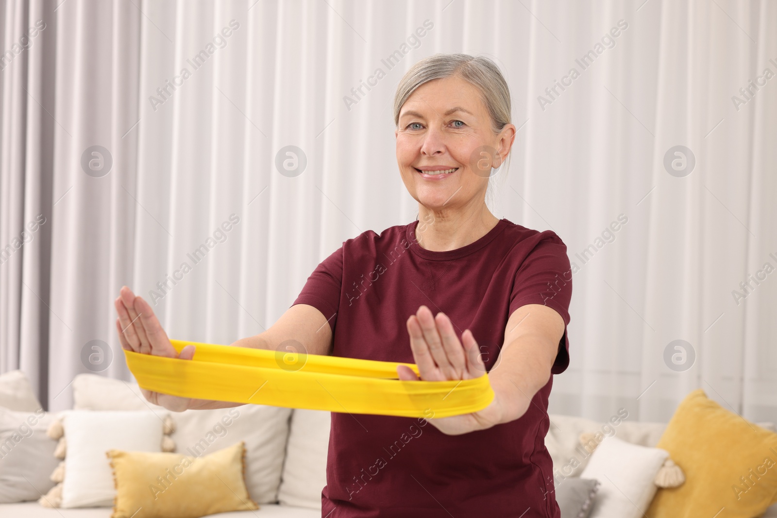 Photo of Senior woman doing exercise with fitness elastic band at home