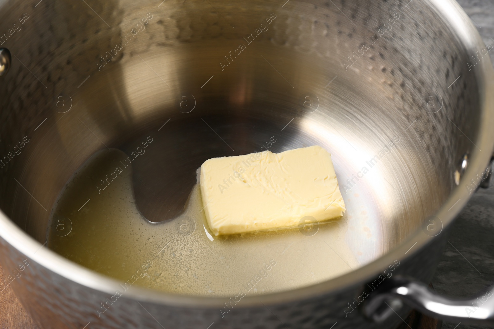 Photo of Piece of melting butter in pot, closeup