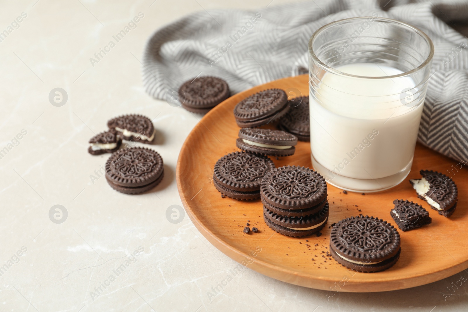 Photo of Plate with chocolate sandwich cookies and milk on table. Space for text