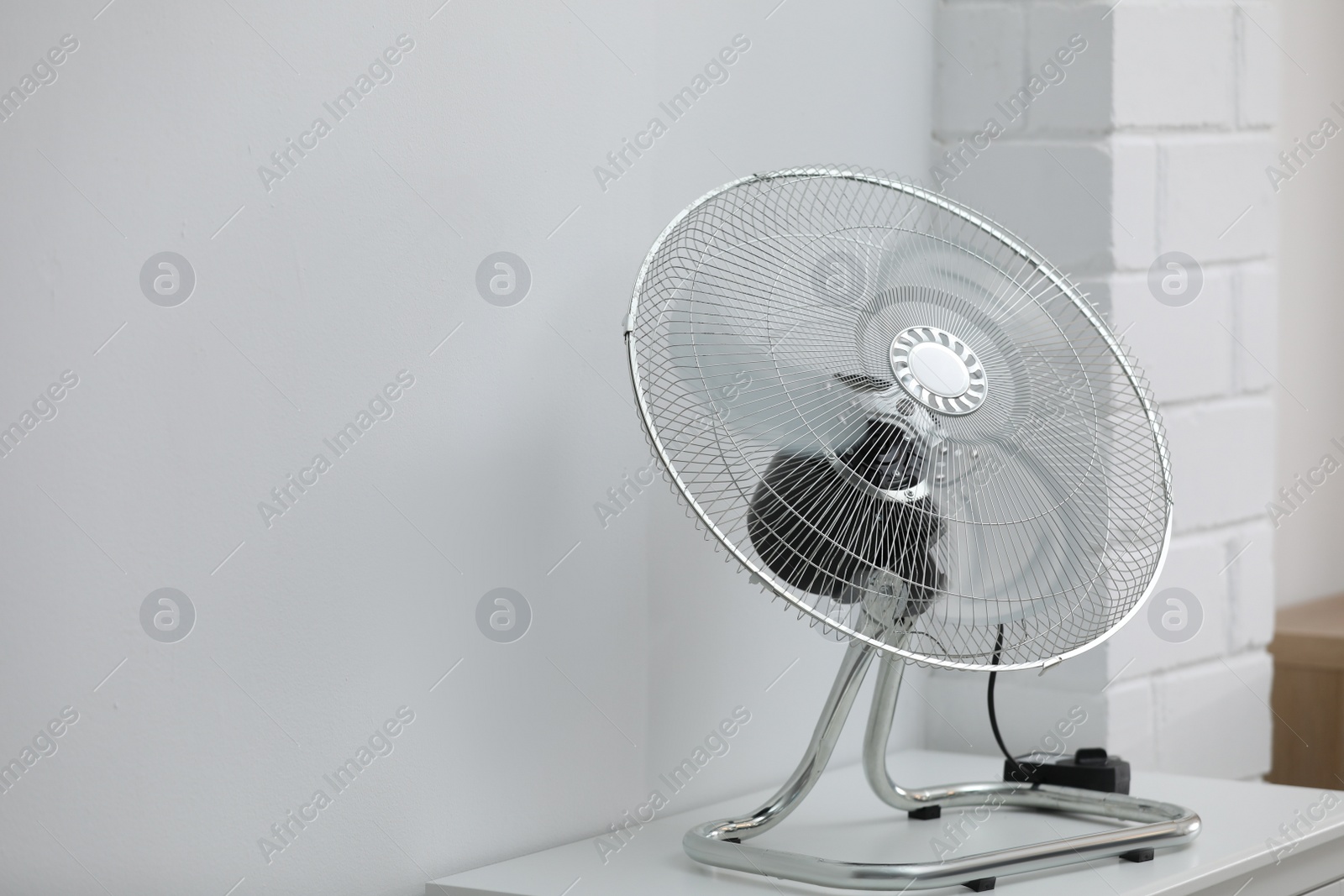 Photo of Modern electric fan on white table indoors. Space for text