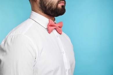 Photo of Man in shirt and bow tie on light blue background, closeup. Space for text