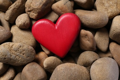 Photo of Red decorative heart on stones, top view