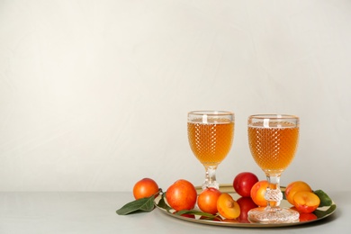 Photo of Delicious plum liquor and ripe fruits on light table. Homemade strong alcoholic beverage