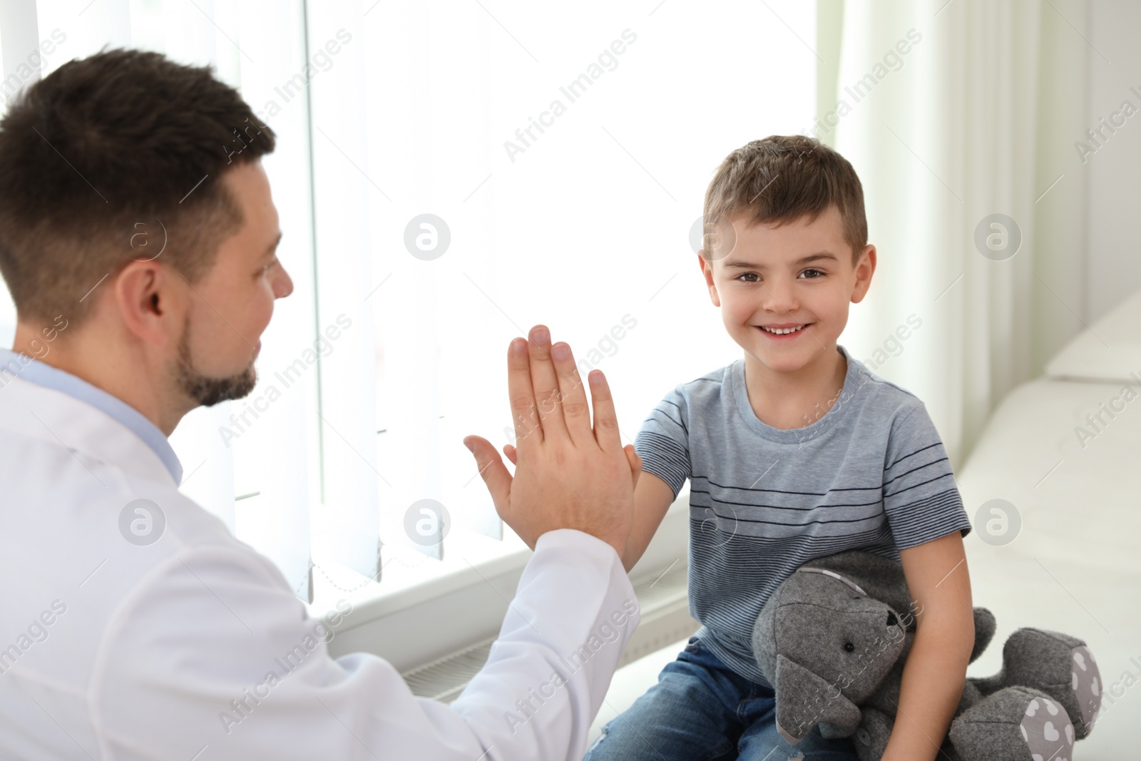 Photo of Children's doctor working with little patient in clinic