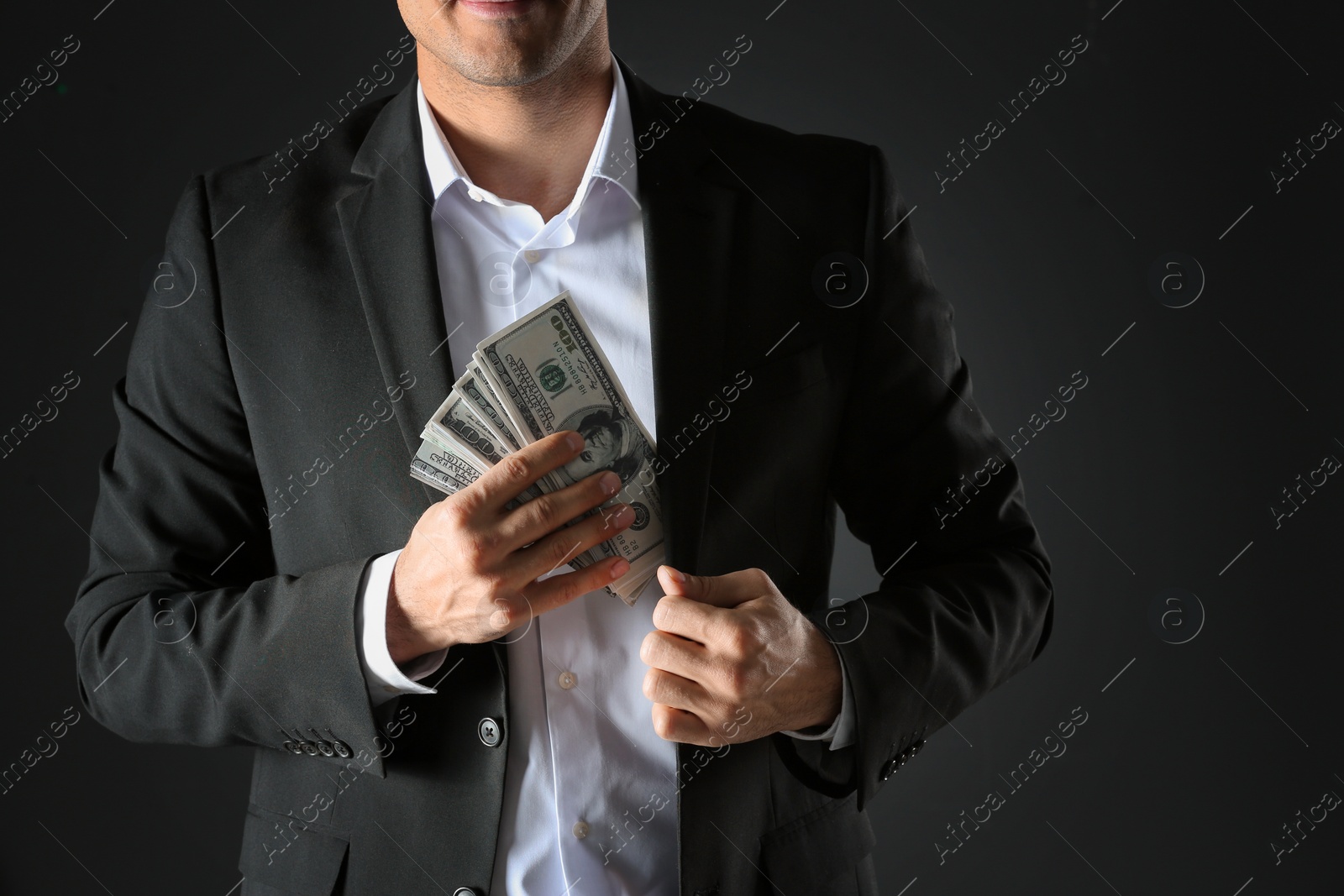 Photo of Man putting bribe money into pocket on black background, closeup