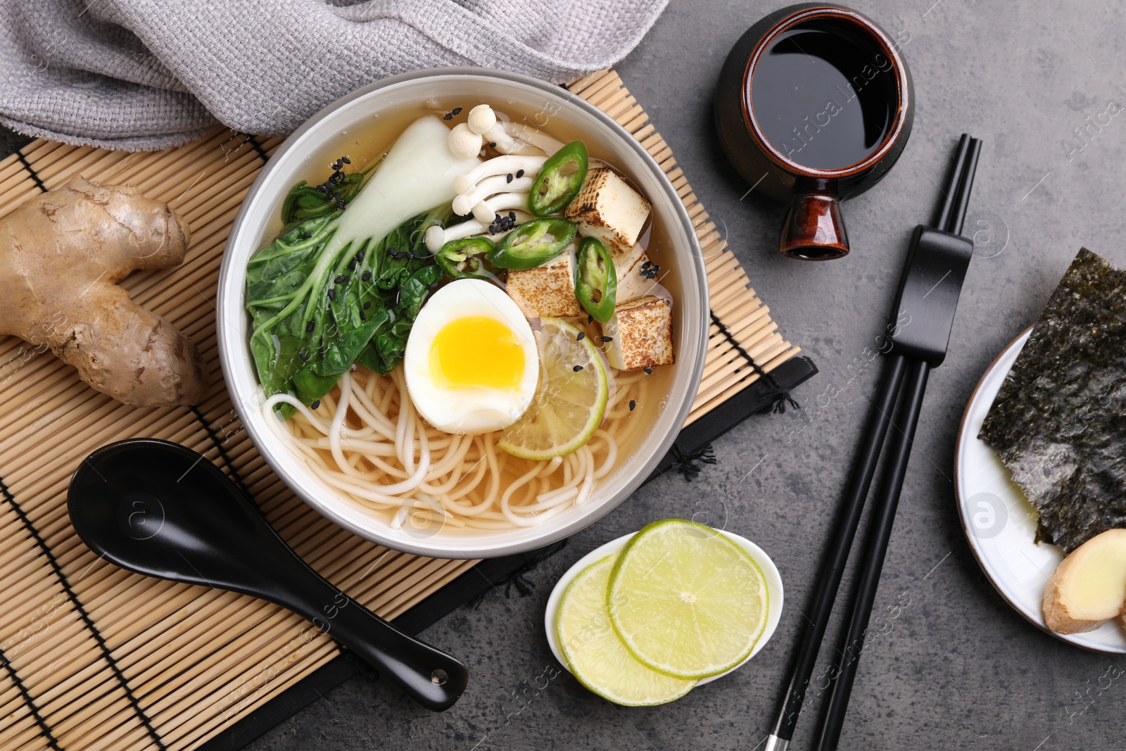 Photo of Vegetarian ramen and ingredients on grey table, flat lay
