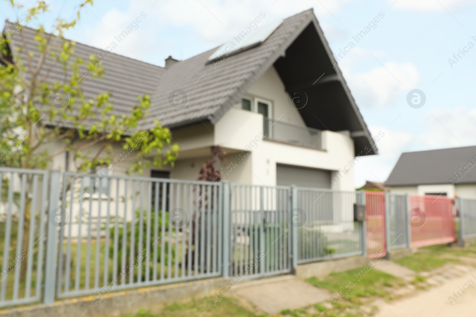 Photo of Blurred view of suburban street with beautiful house behind fence