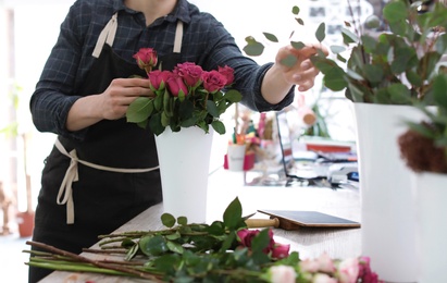 Photo of Male florist creating beautiful bouquet in flower shop