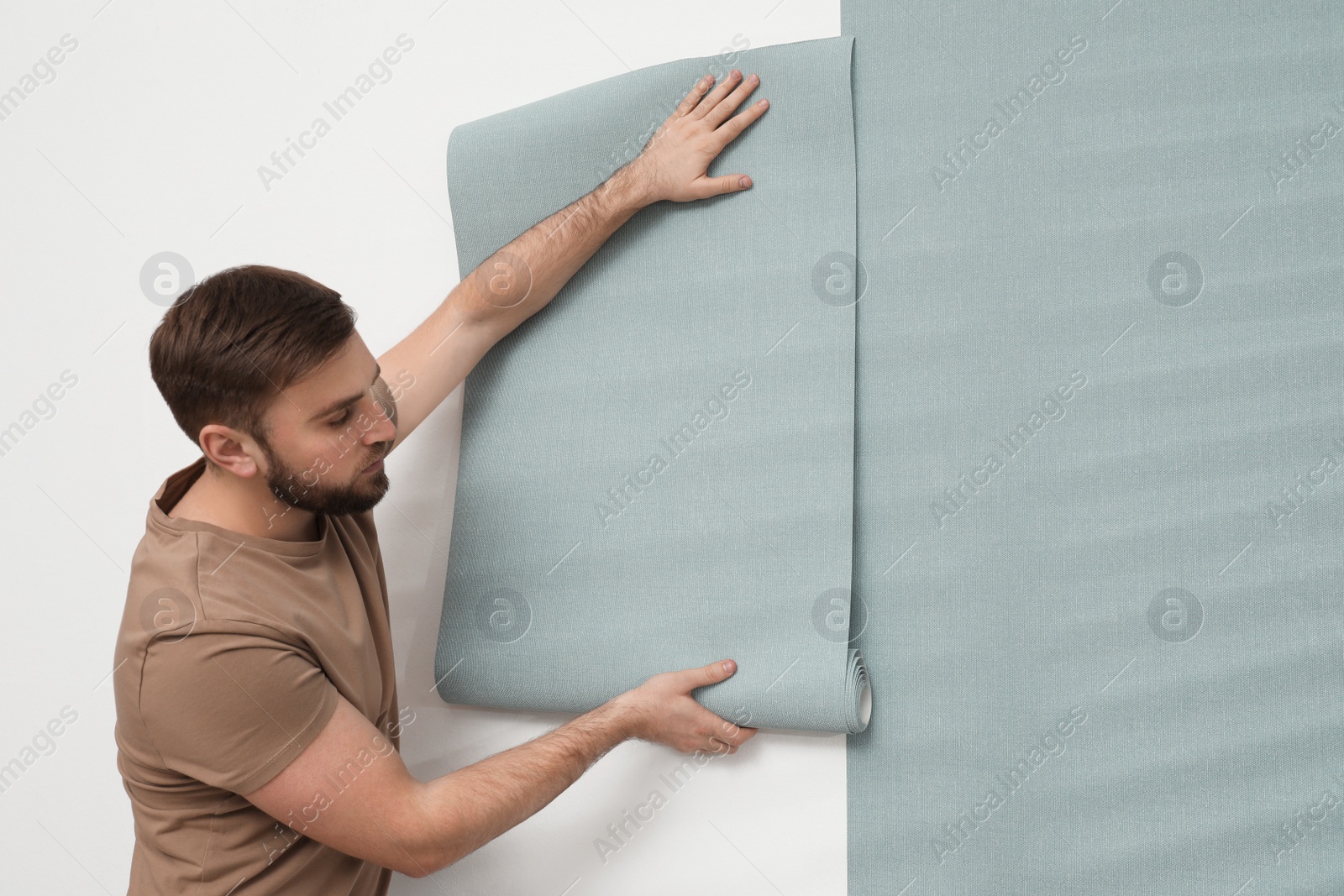 Photo of Man hanging stylish wall paper sheet. Space for text