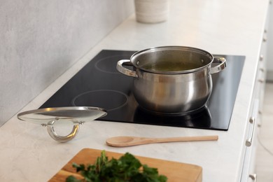 Photo of Pot with tasty soup on cooktop in kitchen