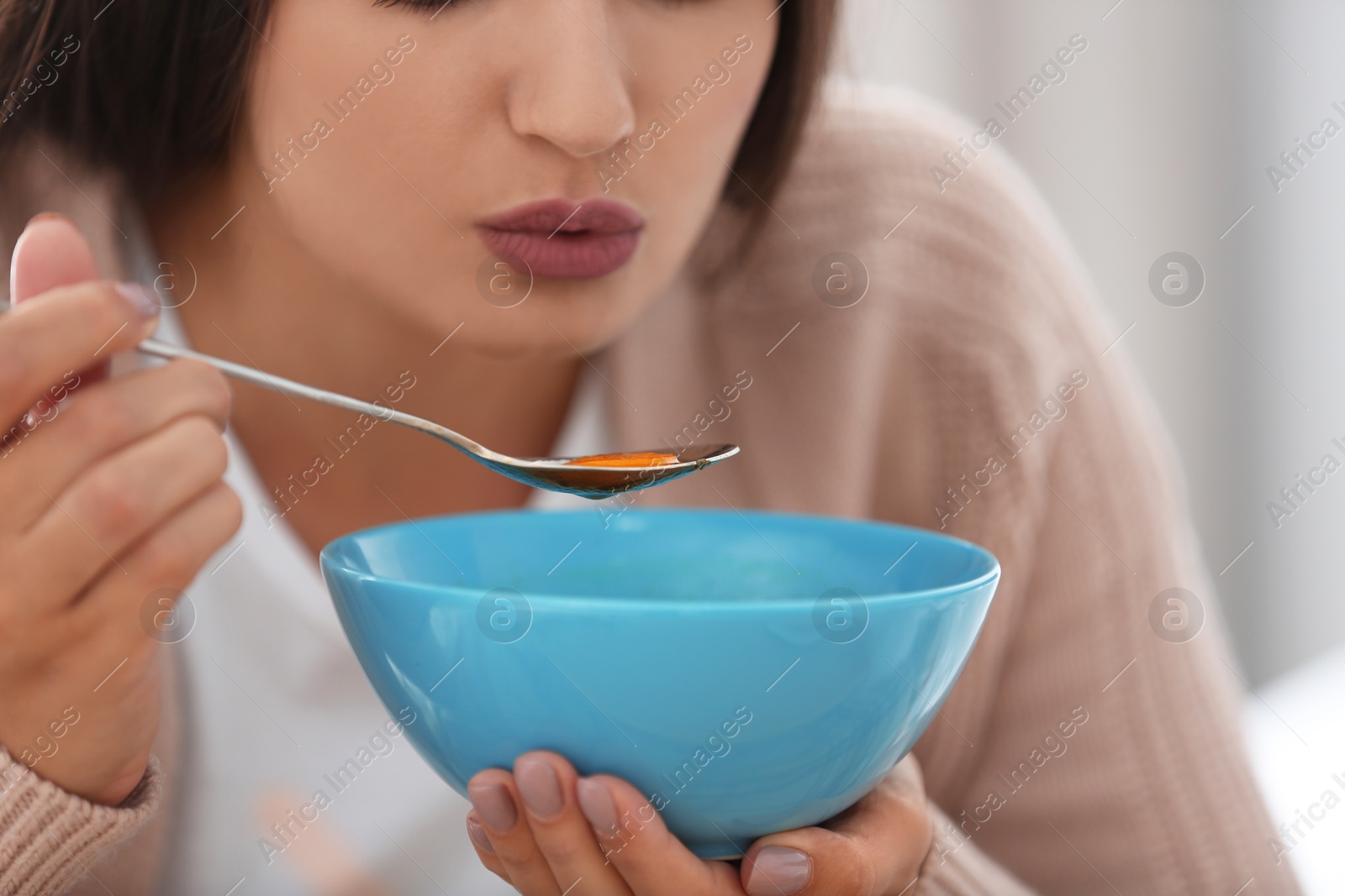 Photo of Sick young woman eating soup to cure flu, closeup