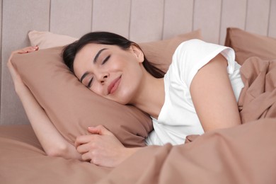 Woman sleeping in comfortable bed with beige linens