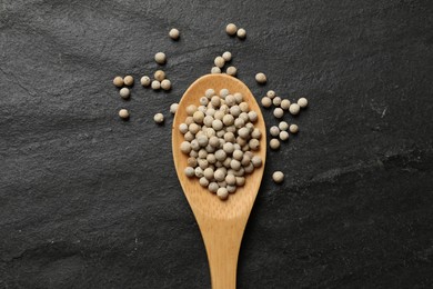 Photo of Aromatic spice. White pepper in spoon on black table, top view