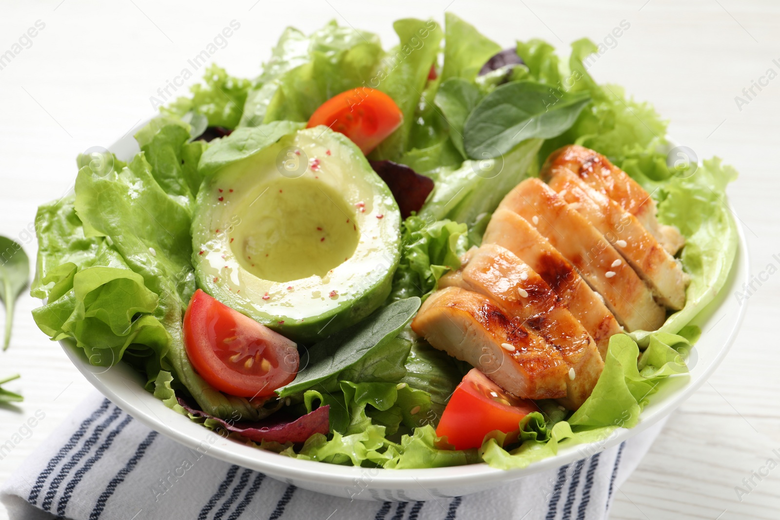 Photo of Delicious salad with chicken, cherry tomato and avocado on white table, closeup