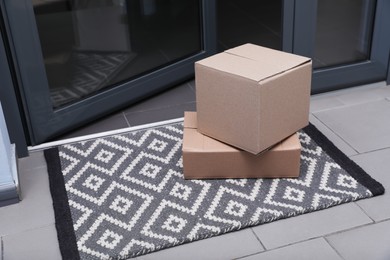 Photo of Cardboard boxes on stylish door mat near entrance