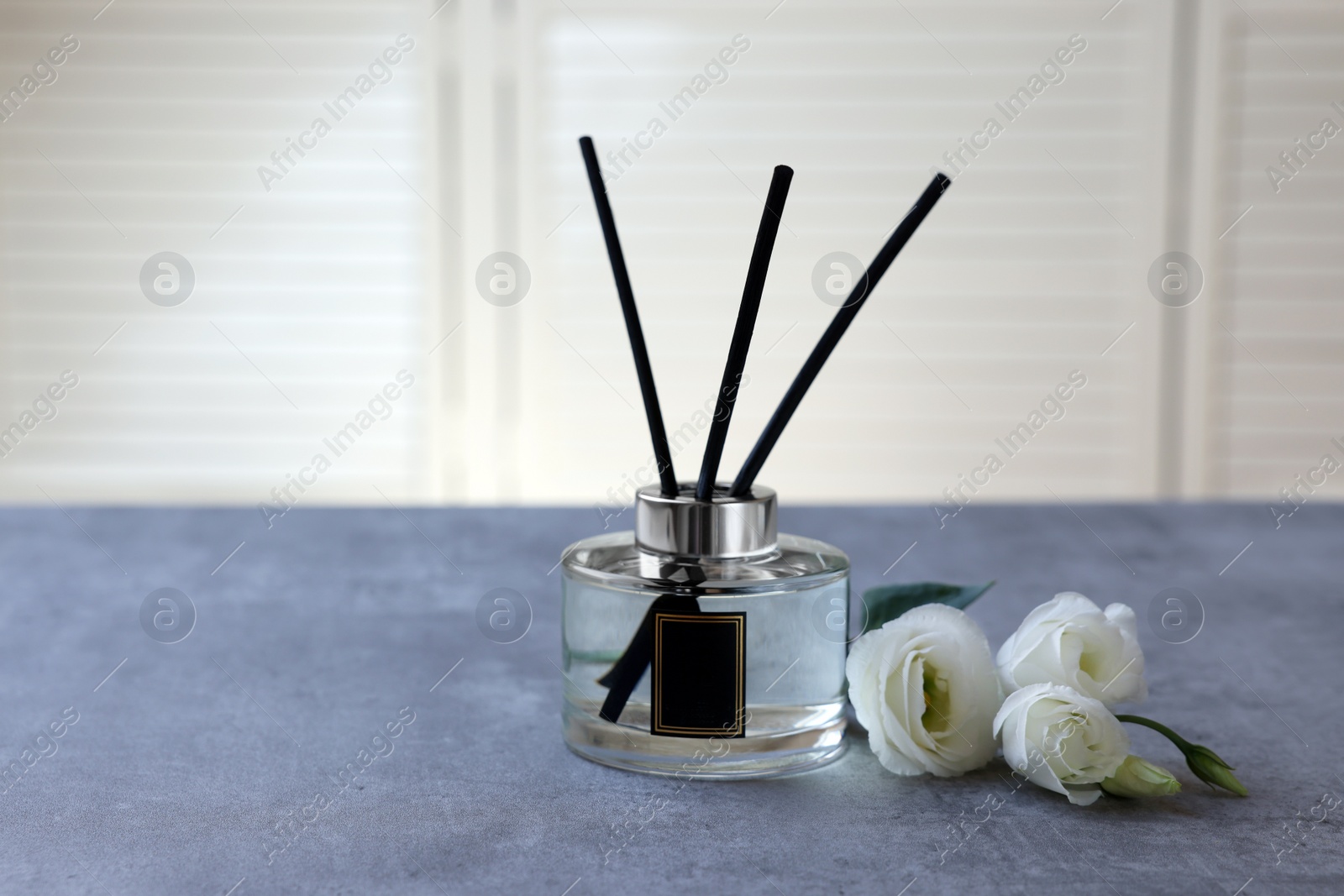 Photo of Reed diffuser and eustoma flowers on gray marble table