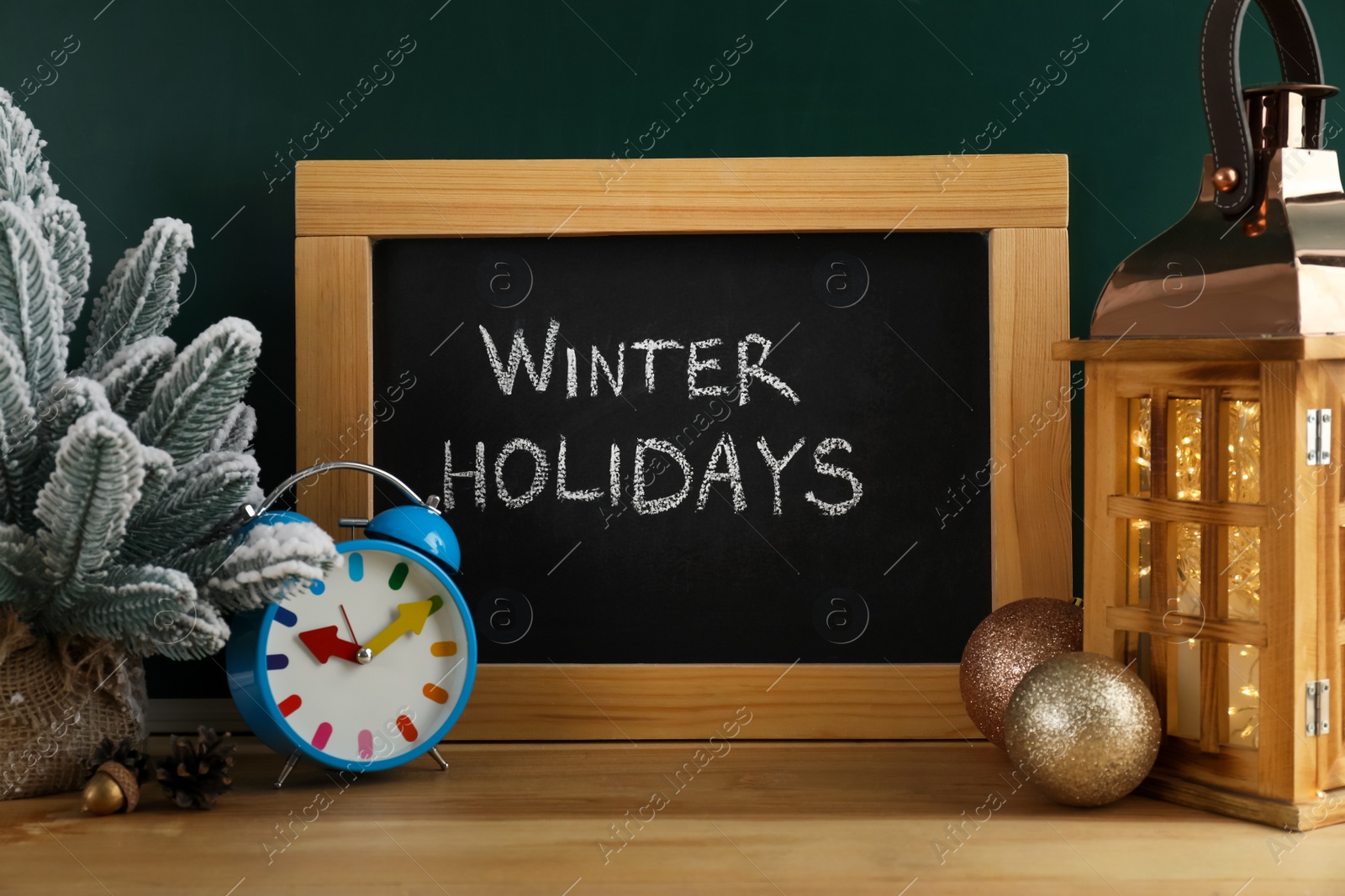 Photo of Chalkboard with text Winter Holidays, alarm clock and Christmas decor on wooden table