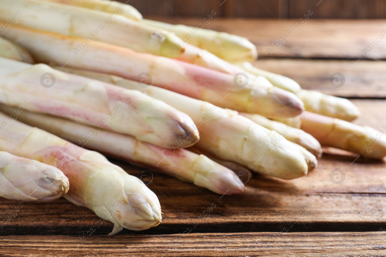 Photo of Pile of fresh white asparagus on wooden table, closeup