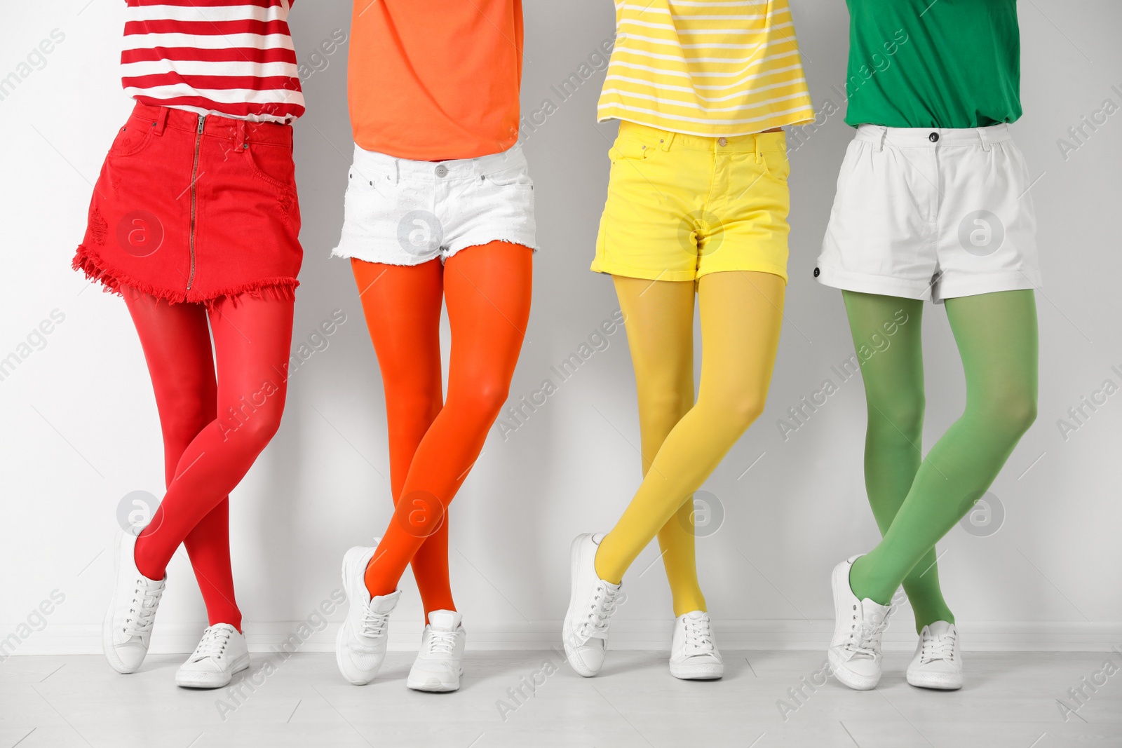 Photo of Women wearing bright tights near white wall, closeup