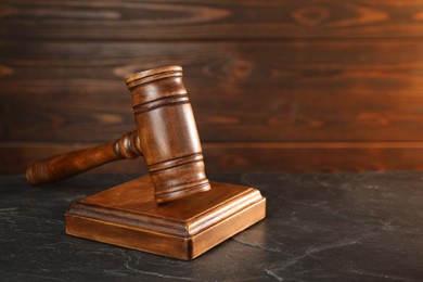 Photo of Wooden gavel and sound block on dark textured table, closeup. Space for text