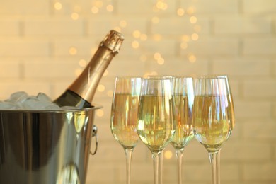 Glasses of champagne and ice bucket with bottle on blurred background