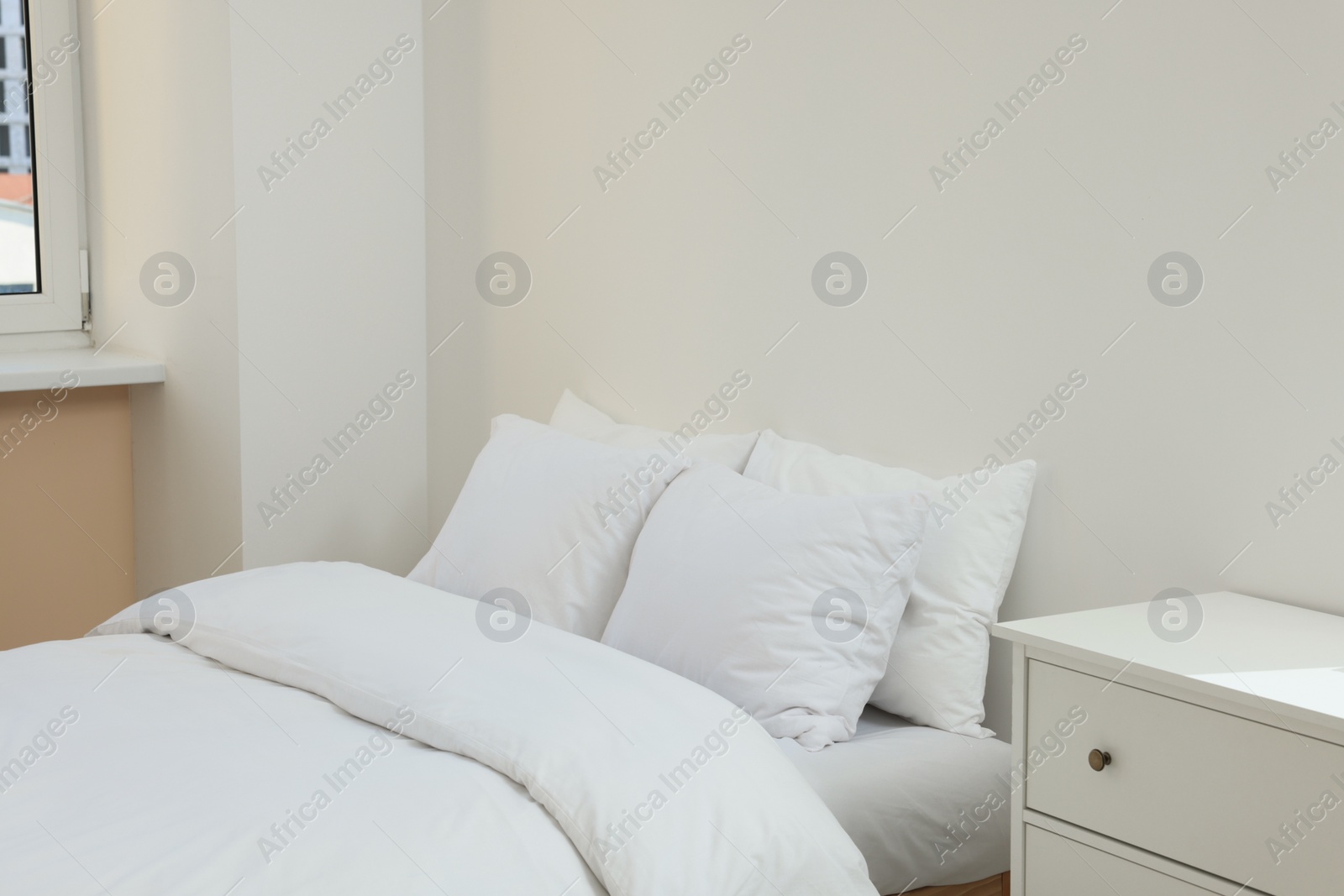 Photo of White soft pillows on cozy bed in room