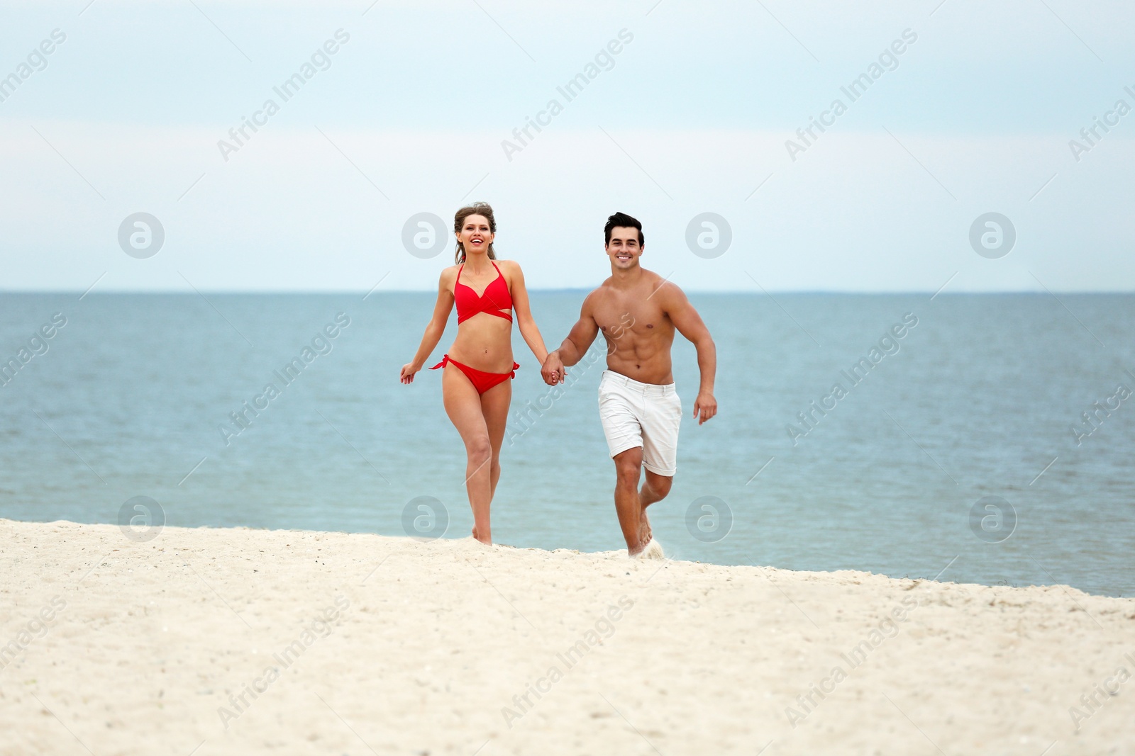 Photo of Happy young couple running together on sea beach