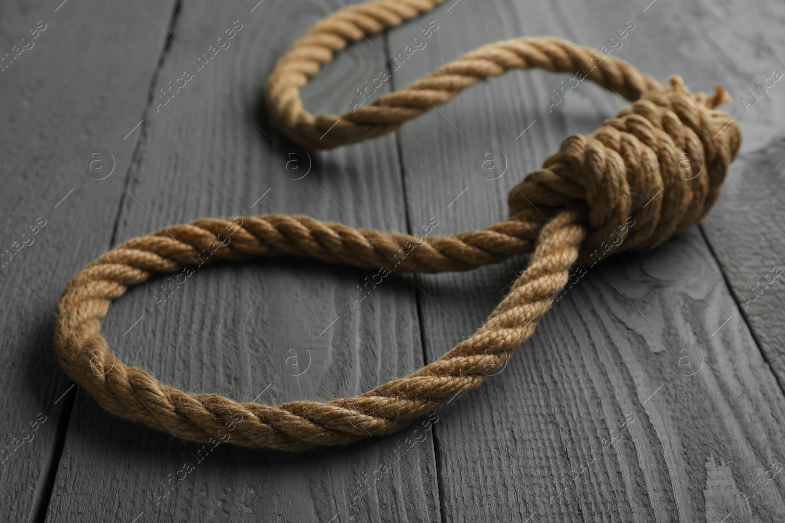 Photo of Rope noose on grey wooden table, closeup