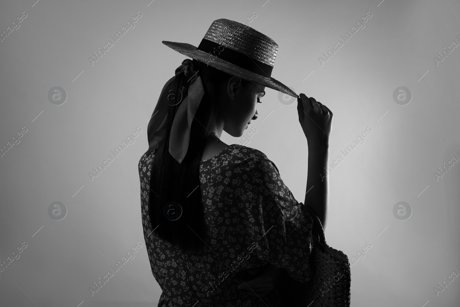 Image of Silhouette of woman wearing hat on light grey background