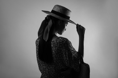 Silhouette of woman wearing hat on light grey background