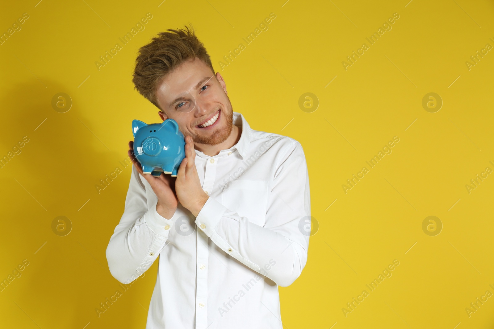 Photo of Young man with piggy bank on color background, space for text. Money saving