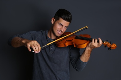 Happy man playing violin on black background