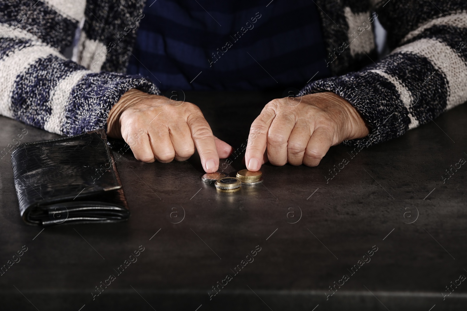 Photo of Poor elderly woman counting coins at table, closeup