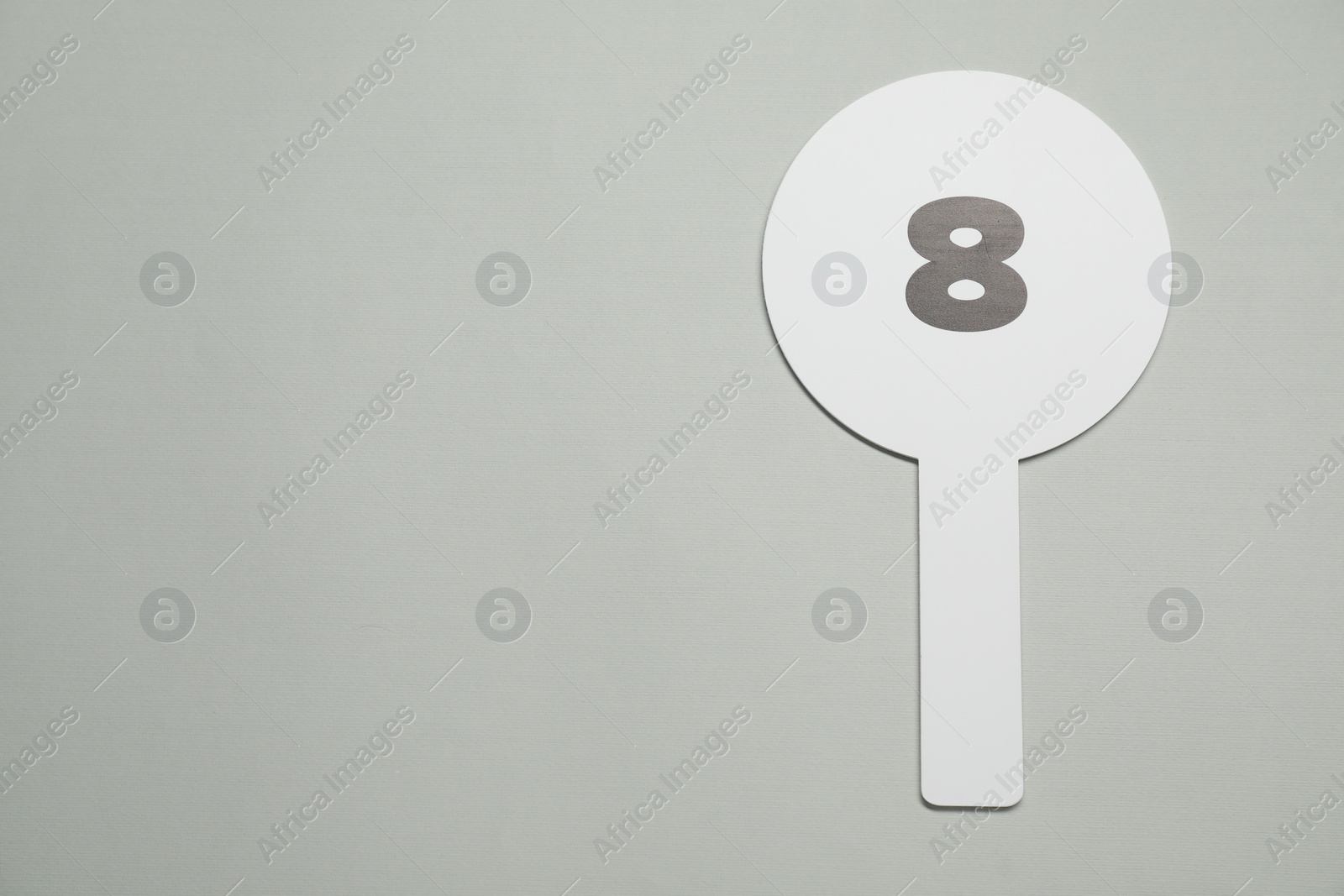 Photo of Auction paddle with number 8 on light grey background, top view. Space for text