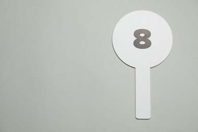 Auction paddle with number 8 on light grey background, top view. Space for text