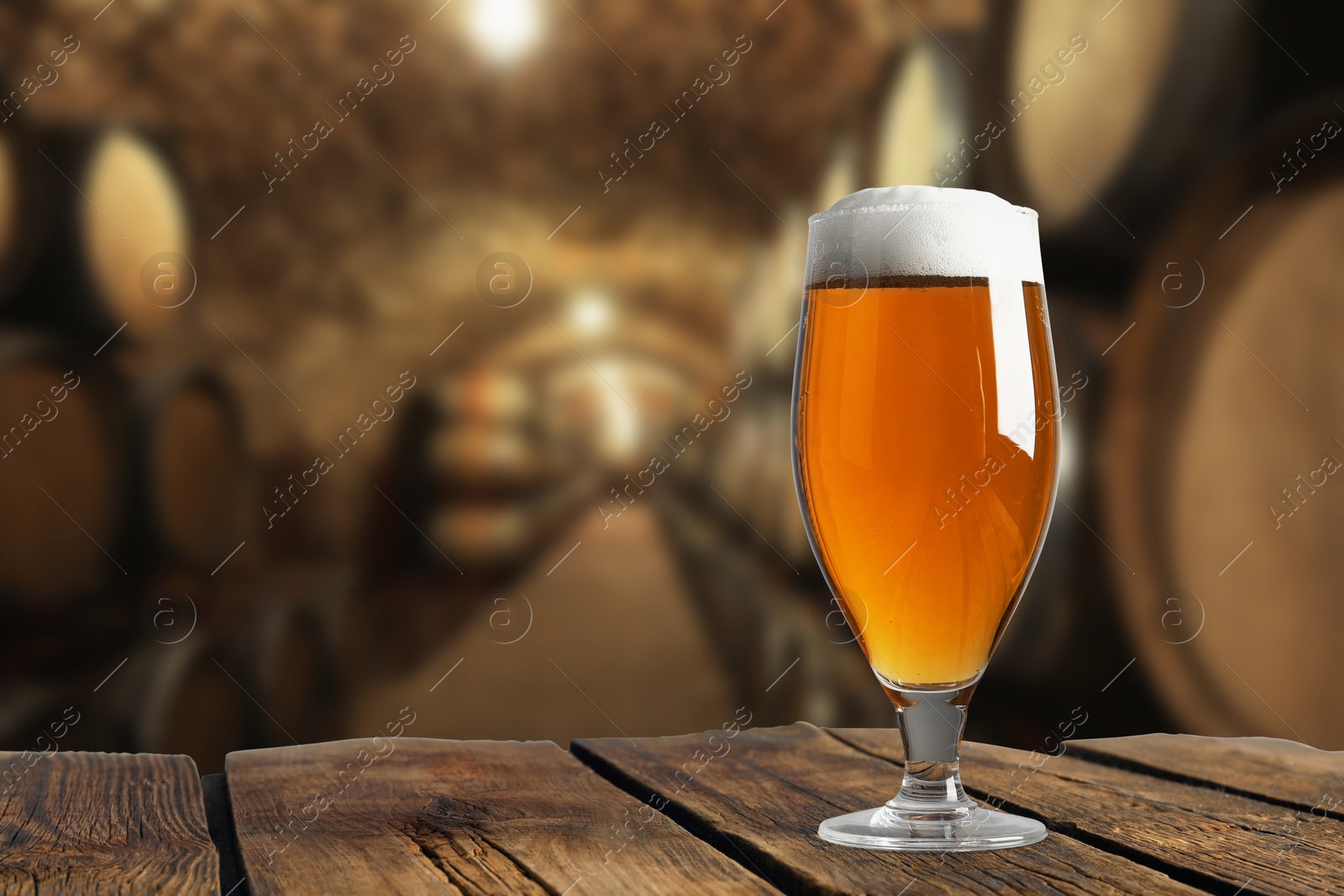 Image of Glass with fresh beer on wooden table in cellar, space for text