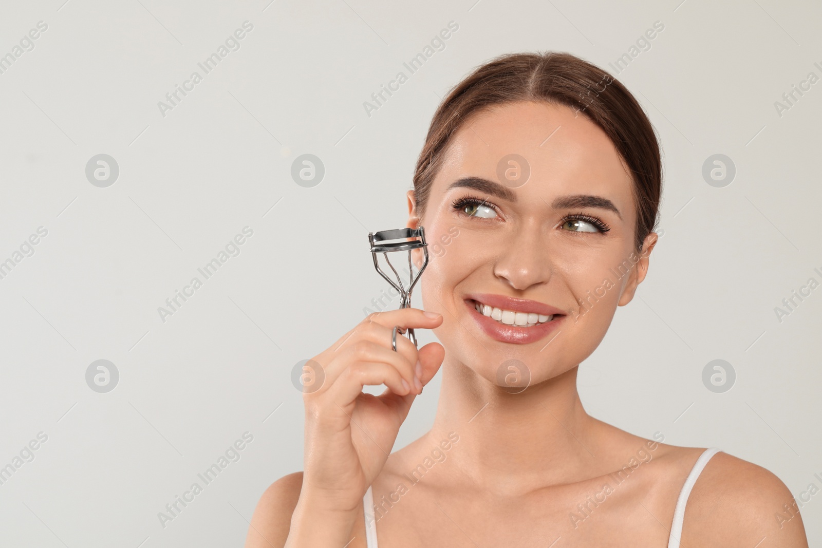 Photo of Woman with eyelash curler on white background, space for text