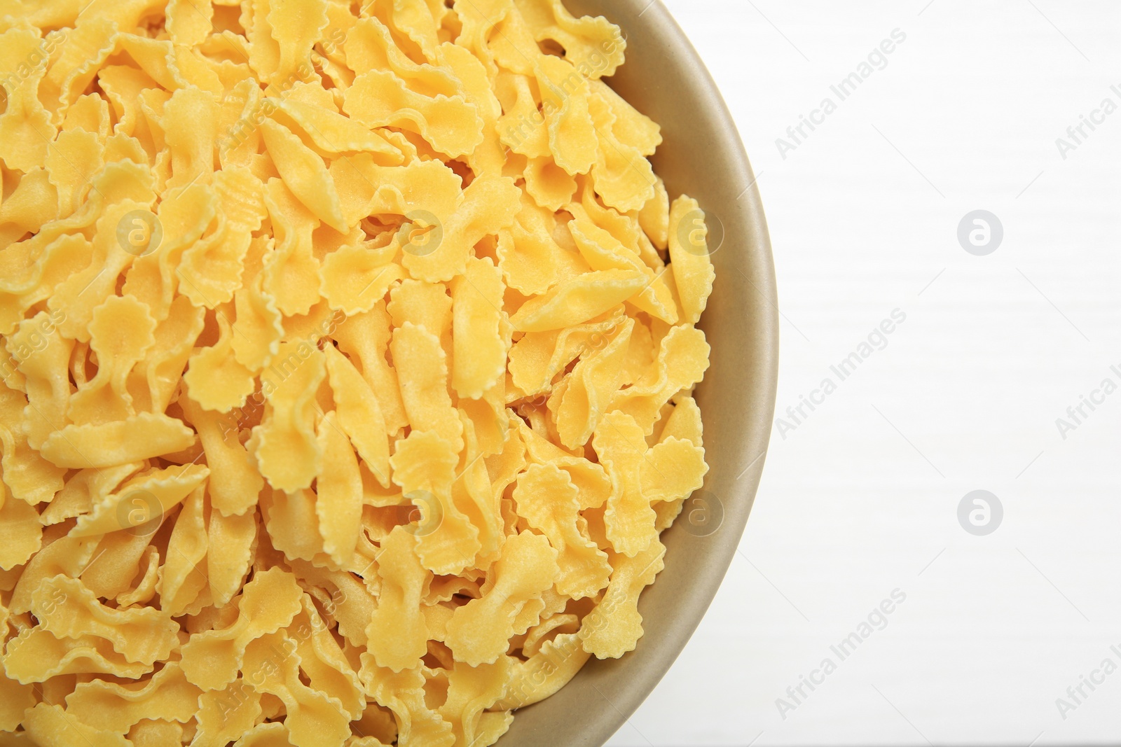 Photo of Raw farfalline pasta in bowl on white table, top view