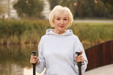 Photo of Senior woman with Nordic walking poles outdoors