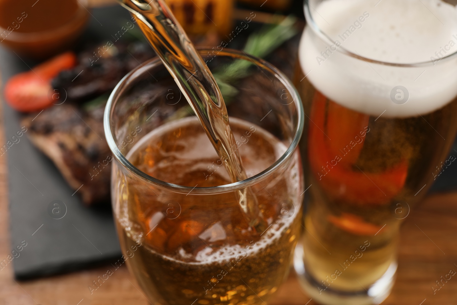 Photo of Pouring beer into glass at table, closeup