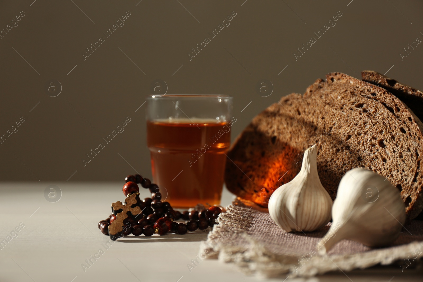 Photo of Rosary beads, garlic, bread and drink on table. Lent season