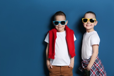Photo of Portrait of cute twin brothers with sunglasses on color background. Space for text