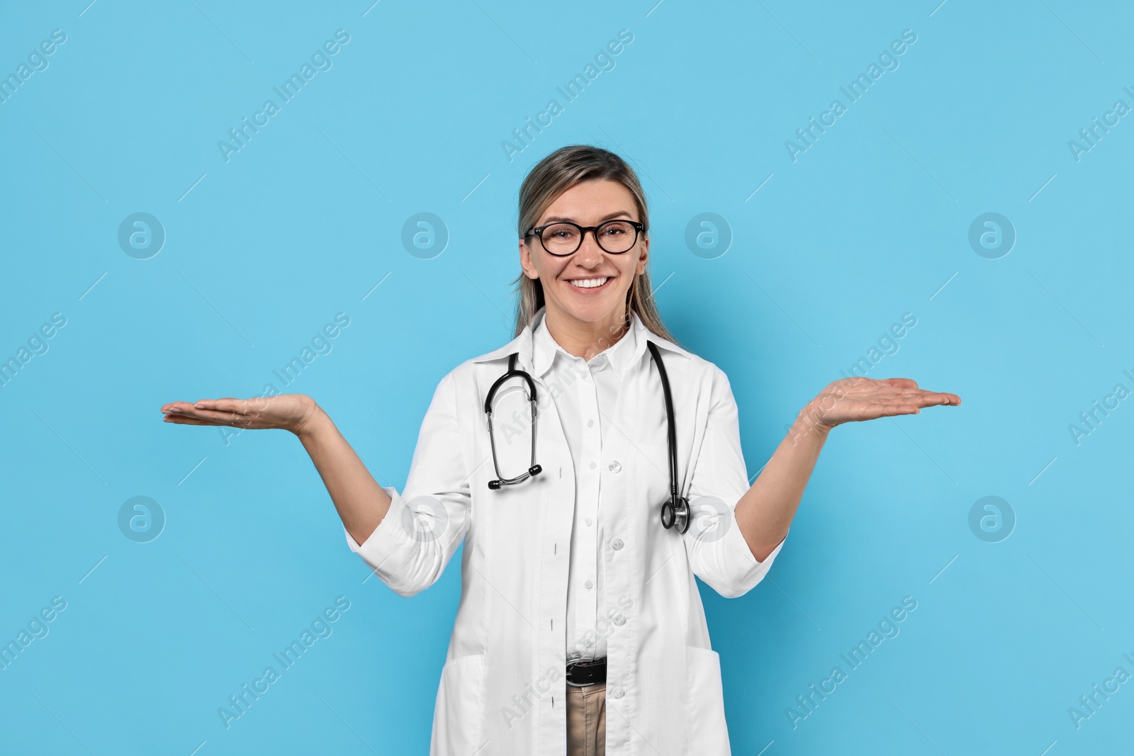 Photo of Portrait of happy doctor with stethoscope on light blue background