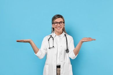 Photo of Portrait of happy doctor with stethoscope on light blue background