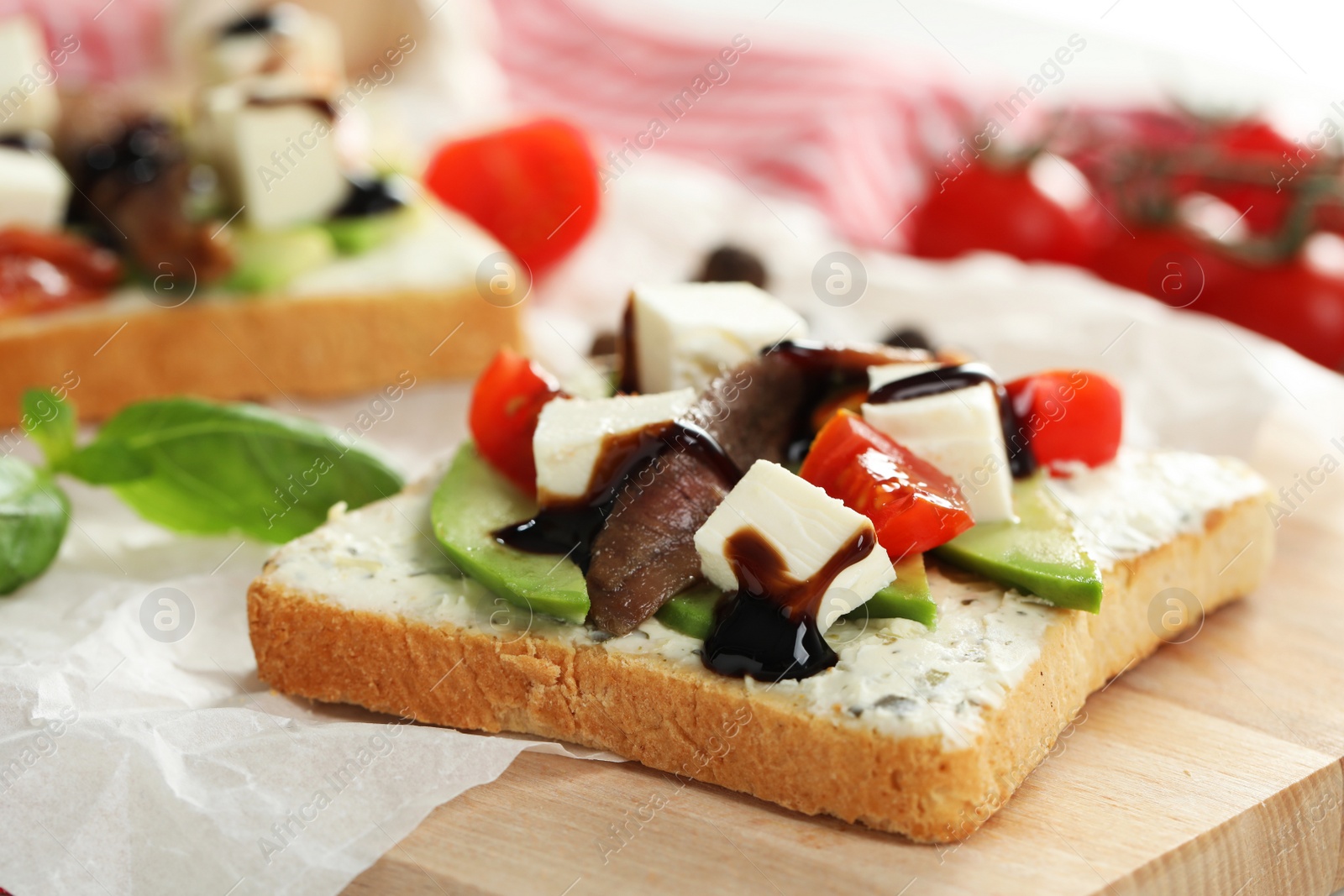 Photo of Delicious sandwiches with anchovies, cheese, tomatoes and sauce on wooden table, closeup